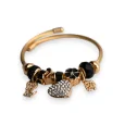 Bracciale rigido charms nero e dorato con cuore di strass