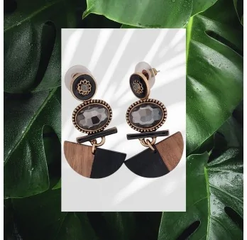 Boucles d'oreilles artisanales en bois, pierre et métal doré sur fond de feuilles vertes Boucles d'oreilles artisanales en bois, pierre et métal doré sur fond de feuilles vertes