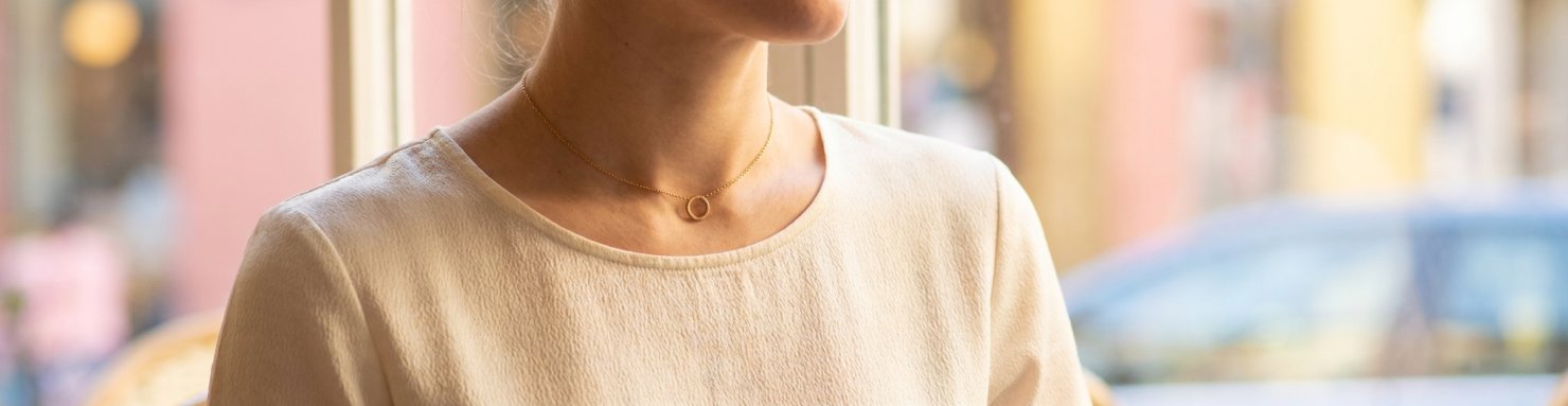 Choker doré porté avec un col rond, bijou court et élégant