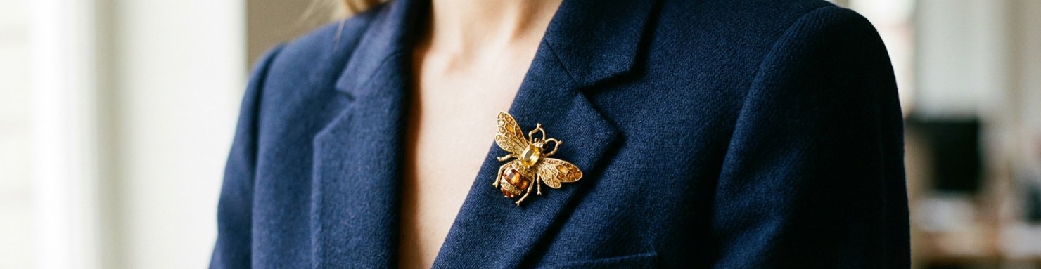 Broche abeille dorée portée sur le revers d un blazer bleu marine