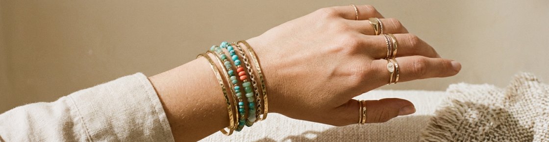 Accumulation de bracelets fantaisie tendance 2026 : joncs dorés, pierres naturelles et bagues empilées