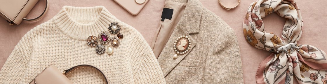 Broches fantaisie posées sur un pull, un blazer et un foulard pour montrer les différents emplacements